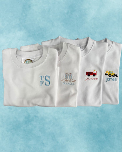 Personalized white tees — monogram, cowboy boots, firetruck, and excavator motifs embroidered with names